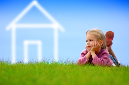 Kind auf Rasen mit Haussymbol